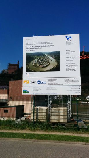 Anhand dieser Luftaufnahme auf einer Bautafel erkennt gut den vom Neckar sehr eng eingeschleiften Hirschhorner Stadtteil Ersheim. Der Hauptort selbst liegt von hier aus gesehen am rechten Bildrand der Luftaufnahme in der oberen Bildhälfte rechts am Neckar.