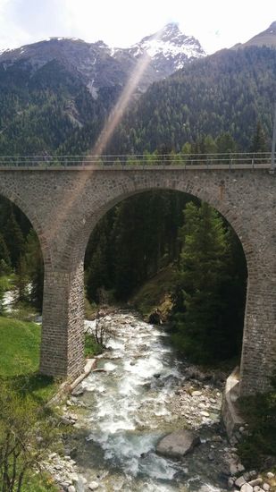 Ein Gebirgsbach rauscht in der Nähe von Brail durch ein Eisenbahn-Viadukt zum Hintergrund, um in den in der nächsten Nähe von rechts nach links tosenden Inn zu münden. Es hätte hier auch eine Fahrmöglichkeit entlang des Inns gegeben, was aber nur für MTBs empfehlenswert war, aber nicht für mein Trekking-/Reiserad.