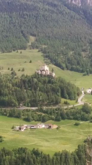 Auf der Abfahrt nach Scuol erscheint aus Blickrichtung Norden auf einem kegelförmigen Felshügel (der Fels ist nur von der  Südseite erkennbar) Schloss Tarasp, das als Wahrzeichen des Unterengadins gilt. Leider konnte ich diese imposante Höhenburg, die auf 1499 m Höhe liegt, mit meinem Handy nicht weiter heranzoomen und im Hinblick auf mein weiteres Vorankommen zum vorgebuchten Ziel  unterließ ich eine weitere Annäherung an das Objekt über die im Bild sichtbare Straße.