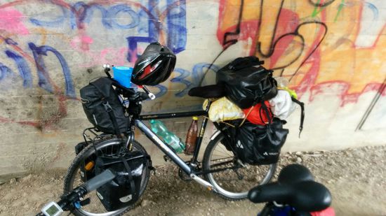 Loic's Edel-Reiserad, Marke Koga Miyata "World Traveller" (im wahrsten Sinne des Wortes).
Am Vorderrad zwei Lowrider-Packtaschen, eine große Lenkertasche und natürlich auch am Hinterrad zwei Gepäcktaschen und zusätzliches Ladevolumen bis gut über Sattelhöhe - ein richtiger Zweirad-Lastesel. Fehlt eigentlich nur noch ein zusätzlicher Lastanhänger, wie ich ihn schon mal vor vielen Jahren bei einem Weltumradler gesehen habe, der durch mein heimisches Feldolling seine Radlspur zog.