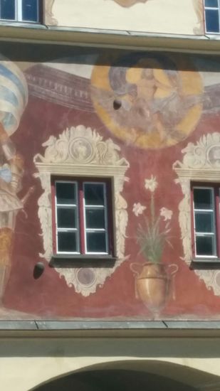 Wasserburg wurde in 1648, also am Ende des Dreißigjährigen Krieges ERFOLGLOS von den Franzosen und Schweden belagert. Wenn ich als Schüler während eines geschichtlichen Klassenausflugs nach Wasserburg richtig aufgepasst haben sollte, vermittelte uns der Geschichtslehrer, daß die beiden Kanonenkugeln im Bereich der gelben Bemalung, sowie am linken unteren Eck des linken Fensters aus der Belagerungszeit stammten. Ob sie jedoch beim Beschuss steckengeblieben sind oder nachträglich eingeklebt wurden, kann ich hier und heute nicht mehr klären.