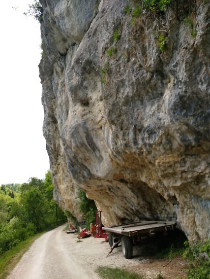 Ein massiver Felsüberhang bildet einen Unterstand für landwirtschaftliche Geräte.