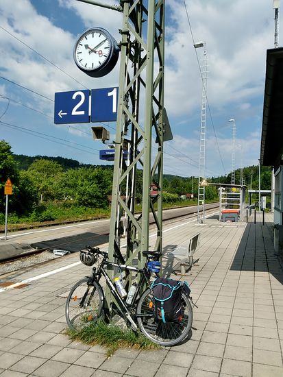 Am Dienstag, 13. Juni 2017 zur zweiten Vormittagshälfte beginnt die Anreise nach Lindau mit der kurzen Radfahrt von Feldolling zum Heimatbahnhof Westerham (für Insider: ab dem Tourenjahr 2019 könnte/sollte/dürfte es lauten "Heimathaltepunkt Feldolling"   ).
Das Grünzeug am Strommasten als Fahrradunterlage wirkt gar nicht einmal störend.
In fünf Minuten kommt (hoffentlich planmäßig) der Zug aus Rosenheim nach Holzkirchen, wo ein kurzer Umstieg nach München, allerdings am selben Bahnsteig gegenüber, erforderlich ist.