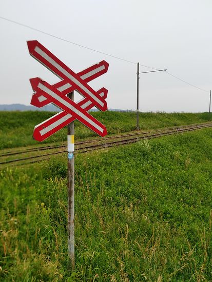 Bahnübergang an einer elektrifizierten Feldbahn-Strecke.