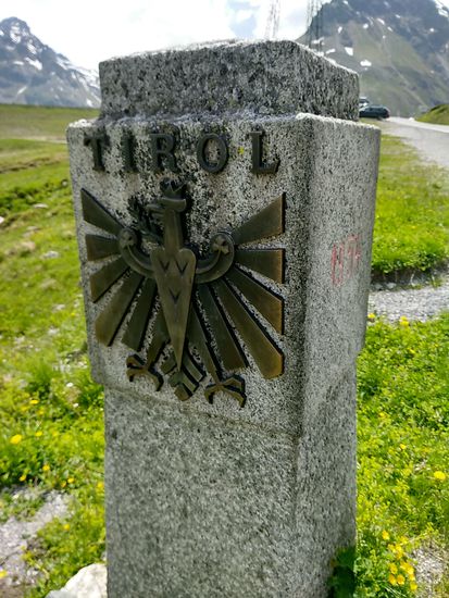 Noch vor der ersten Kurve bzw. Kehre, wie auch immer, der Grenzstein ins Bundesland Tirol. Hier in "Open-Air-Version" und nicht wie weiter nördlich auf der Arlbergstrecke mitten im Arlbergtunnel, wo so ein dekoratives Stück gar nicht vorhanden sein dürfte.