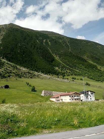 Hinter den beiden Anwesen sieht man eine der mächtigen steinernen Lawinenschutzmauern gegen zukünftige Abgänge.