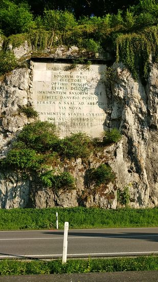Doch vorher noch eine mächtige, in Stein gehauene Gedenktafel an den Kurfürsten Carl Theodor von Bayern. An dieser Stelle ließ er mehrere Felsensprengungen durchführen, um die im Flußbett oder hart am Flußufer verlaufende und somit häufig von Überflutungen heimgesuchte Straße von Saal nach Abbach zu verbreitern und höher legen zu können.