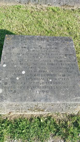 Auf einer im Boden auf der Seite meines Radwegs angebrachten Steintafel ist der lateinische Lobestext an der Felswand in deutscher Schrift verfasst.