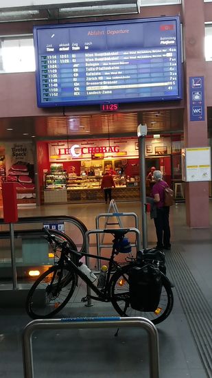 In Innsbruck Hbf angekommen bekam ich wegen dieses Erinnerungsfotos vor der großen Abfahrtsanzeige in der Bahnhofshalle auch noch eine kleine Rüge vom Sicherheitsdienst, da mein Rad für etwa eine halbe Minute die links angrenzende feste Treppe versperrte, obwohl diese ja selbst zu diesem Zeitpunkt für eine Benutzung gesperrt war.
Was soll's, man kann auch übertreiben. Ganz unten auf der Anzeige wird mein REX (Regionalexpress) nach Landeck-Zams angezeigt.
