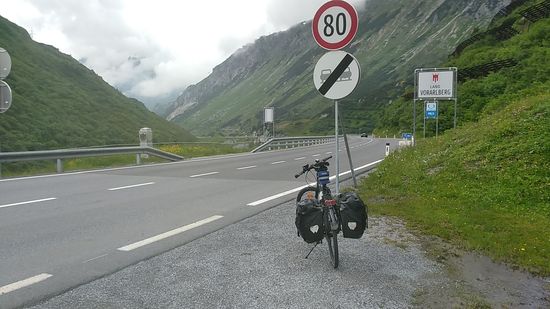 Kurz nach der Passhöhe erreicht man das Bundesland Vorarlberg (großes weißes Hinweisschild - auf der gegenüberliegenden Straßenseite der Tiroler Grenzstein.