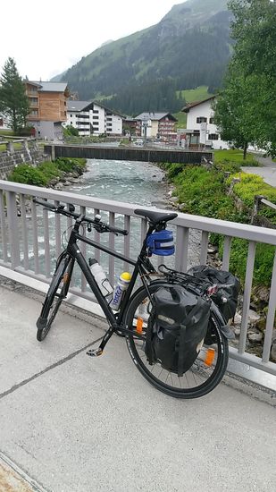 Nach einer zügigen Bergabfahrt durch eine längere und eine kürzere Schutzgalerie zwischen den Ortschaften Zürs und Lech kreuze ich auf einer Höhe von 1444 m über der Adria in Lech auf einer Brücke zum ersten mal den Hauptdarsteller dieser Reisebeschreibung, 
den noch bachartigen Fluß Lech, der in Blickrichtung abwärts fließt.
Der Lech entspringt dabei auf 1840 m Höhe in der Nähe des Formarinsees und mündet nach 256 km Länge auf 392 m Höhe zwischen Rain und Marxheim in die Donau.
Ab dieser Brücke ist der Lech bis zur Donaumündung noch etwa 242 km unterwegs, wobei ich ihn bestmöglich auf mit dem Fahrrad befahrbaren Straßen und Pfaden begleiten werde (oder er, der Lech, mich).