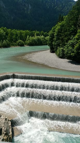 Am südlichen Stadtrand von Füssen strömt der Lech aus dem Hintergrund auf den Lechfall zu.