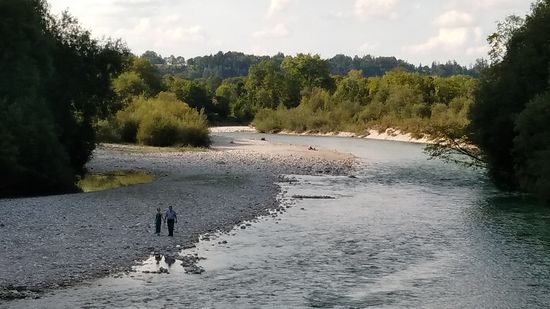 In der Vergrößerung ein Duo Hand in Hand beim romantischen Spaziergang am Isarufer.