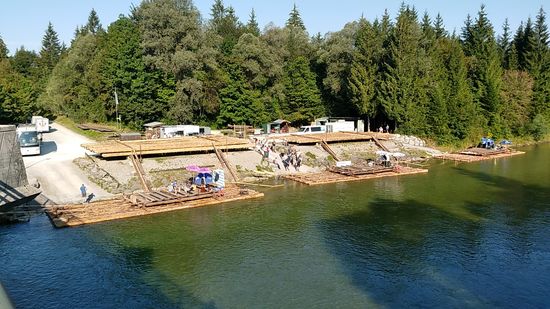 Dort angekommen ergibt sich ein schöner Ausblick auf den Startplatz für die beliebten Isar-Floßfahrten, die bis zur Floßlände in der Nähe des Tierparks München-Thalkirchen führen.
Für die 28 km lange Fahrt benötigen die ca. 20 to schweren und 18 m langen Flöße für max. 60 Personen, die auch heute noch nach alter Handwerkskunst zusammengebaut werden, je nach Wasserstand 5-7 Stunden.