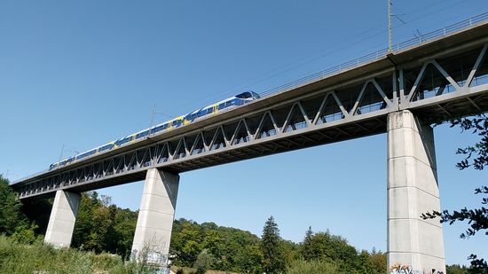 Die Großhesseloher Brücke wurde von 1851-1857 errichtet und dient dem Eisenbahnverkehr auf der Strecke München-Holzkirchen und dann weiter nach Rosenheim (der "Meridian"-Triebwagen auf der Brücke war nach rechts in Richtung Rosenheim unterwegs) bzw. ins Oberland in den drei Ästen nach Bayrischzell, Tegernsee und Lenggries, das ja schon entlang des jetzt beschriebenen Isarradwegs liegt.
Die jetzige zweite Brücke, die von 1983-1985 neu gebaut wurde, bietet innerhalb der Fachwerkskonstruktion unter der Schienenstrecke einen breiten Rad- und Fußweg und stellt eine Variante des Radl-Rings um München dar. 
Aus eigener Erfahrung kann ich sowohl aus zahlreichen Querungen mit der Bahn, wie auch mit dem Fahrrad, den herrlich spektakulären Blick auf das Isartal und das beginnende südliche München aus ca. 42 m Höhe anpreisen !
Allerdings blieb ich, wie den ganzen Tag, auf der rechten Isarseite, hätte aber im Nachhinein relativ leicht ein, zwei Fotos vom Untergeschoss aus knipsen können.
Echt schade, aber da habe ich zu wenig weit gedacht.