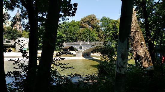 Links oben ist nochmals ein Teil von St. Lukas erkennbar.
In Bildmitte liegt der unter Denkmalschutz stehende Kabelsteg in Form einer Bogenbrücke, die 1898 eröffnet wurde.
Die Gesamtlänge der die "kleine Isar" überspannenden zwei geschwungenen Bögen beträgt 76,50 m, wobei die am linken Ende befindliche Praterinsel mit dem hier rechts befindlichen Ostufer der Isar verbunden wird.
Die Fortführung von der Praterinsel zum Isar-Westufer über die "Große Isar" wird dann Mariannenbrücke genannt.
Auffällig am Kabelsteg ist die Öffnung über dem Pfeiler zwischen den zwei Bögen, die sowohl das Brückengewicht, als auch die Widerstandsfläche gegenüber einem massiven Hochwasser reduzieren soll. 
So überstand der Kabelsteg ein Hochwasser im September 1899, dem die Luitpold- und Max-Joseph-Brücke zum Opfer fielen, recht gut.