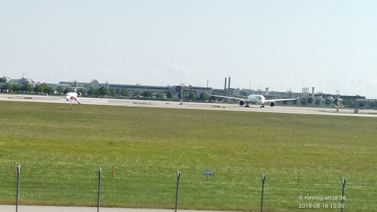 Rechts im Bild eine der aktuellen zweimotorigen Ultralangstreckenmaschinen 
vom Typ Airbus A 350-900, kurz vor dem Einschwenken in die Startbahn in Ruhe verharrend, da erst noch ein im Landeanflug befindlicher Jet Vorrang hat.