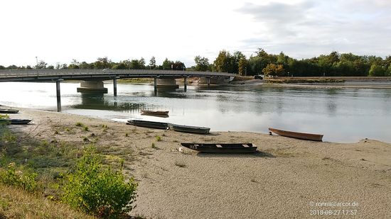 An der Brücke von Teisbach zum auf der anderen Isarseite gelegenen Dingolfinger Gebiets sind mehrere Boote auf dem trockenen Strand geparkt.