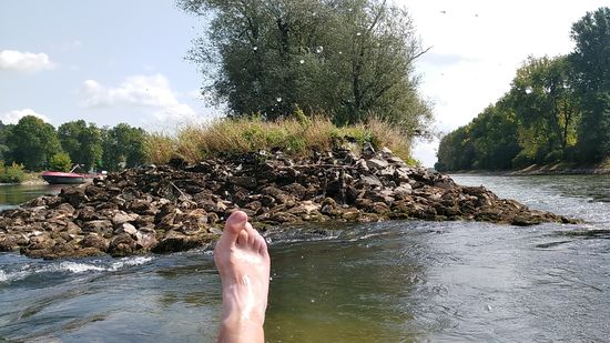 Im Bereich der vorausliegenden Baumgruppe sieht man durch das Planschen mit dem Fuß nach oben fliegende Wassertropfen.