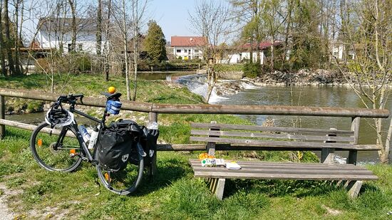 In Aham bei Frontenhausen ist kurz nach 14 Uhr die für mich bei Radferntouren übliche verspätete Mittagspause in Form von Wurstsemmel, Apfel (auf dem Sattel) und Tetra-Pak Fruchtsaft anhängig. 
Die beiden Wasserflaschen am Fahrradrahmen mit leicht gesalzenem Leitungswasser waren seit der Abfahrt von zu Hause nicht angetastet und in der Erinnerung denke ich, diese in der ersten Unterkunft entleert und anderntags nach dem Frühstück durch frischen (evtl. wieder unnötigen) Gewichtsballast ersetzt zu haben. Aber es ist ja erst Mitte April mit (angenehm) frischen Temperaturen.