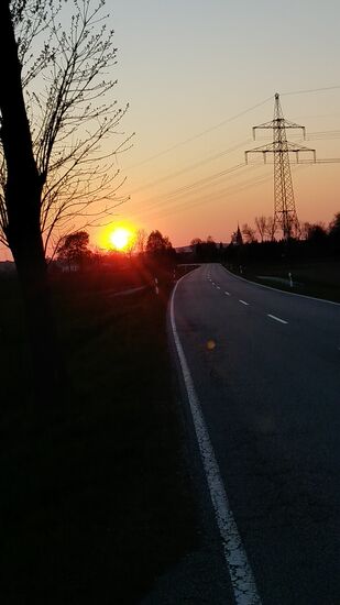 Bei Heinrichsdorf, knapp 4 km vor Aldersbach gibt's noch einen kurzen Fotostopp, um gegen meine Fahrtrichtung die gerade noch in ihrer vollen Größe erscheinende Sonne vor ihrem nahenden Untergang festzuhalten. Zusätzlich noch schnell eine wärmende Jacke und eine Warnweste bei der jetzt merklich kühlen Abendtemperatur und fortschreitenden Dämmerung übergezogen und praktisch um Schlag 20 Uhr nimmt mich die gerade noch anwesende Dame an der Rezeption in Empfang, so daß die "Dramaturgie" dieser Quartierssuche am ersten Tag ein angenehmes Ende mit sich brachte.