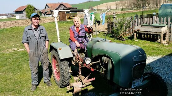 Zwischendrin eine nette, menschlich geprägte Episode:
Beim Passieren eines Anwesens kam ich mit dem im Garten beschäftigten Hausherrn ins Gespräch, der auch aus früherer Zeit als Lkw-Fahrer meine Heimatgegend kannte und dieses Gespräch zog sich auch etwas in die Länge. 
So nebenbei bot er mir ein großes Glas Honig aus seiner eigenen Imkerei an (hinter der Traktorfahrerin sieht man das "Bienenhotel"). Nach kurzer Zeit ertönt aus der Nachbarschaft ein Traktor und er (Hans) kündigt an, daß gleich die Lisi mit ihrem Gefährt erscheinen wird. 
Auch mit ihr entwickelt sich ein nettes Gespräch und sie bietet mir freiweg einen der Äpfel an, die sie mit sich führt.
Wenn das kein Verpflegungsservice ist, dann weiß ich auch nicht mehr weiter.
Das nennt man Herzlichkeit.
Servus Lisi und Hans !