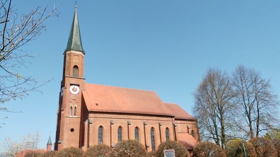 Nach ca. 5 km Fahrstrecke vom Rottauensee durchfahre ich Hebertsfelden mit ihrer katholischen Pfarrkirche St. Emmeram. Auf einem Tafelbild anno 1688 links des Hauptaltars ist die frühere spätgotische Pfarrkirche zu sehen, die 1854 im Zusammenhang mit Bauarbeiten eingestürzt war und von 1859 - 1862 durch den gegenwärtigen Blankziegelbau - wiederum im gebietstypischen spätgotischen Baustil - ersetzt wurde.
Übrigens - wie man sich doch täuschen kann:
Beim Knipsen des Fotos während der Tour fiel mir das Objekt gar nicht auf. Beim Verfassen des Berichts wollte ich feststellen, um welche weitere Kirche es sich handelt, die links des Kirchturms aus der Ferne zu erkennen ist.
Weder auf Google Maps wird eine entsprechende Kirche angezeigt, noch auf der Suchmaschine selbst wird bei den Ortskirchen der Umgebung anhand einer Abbildung eine entsprechende Kirche beschrieben.
In höchster Erklärungsnot und um drohende Schlafstörungen in der anstehenden Nachtruhe zu vermeiden   , setzte ich eine Email mit Bitte um Klärung des Sachverhalts an die Gemeindeverwaltung von Hebertsfelden ab, was auch zügig am folgenden Vormittag beantwortet wurde:
Es ist keine weitere Kirche im Hintergrund, sondern die sogenannte "Grotte", die direkt neben St. Emmeram steht.  