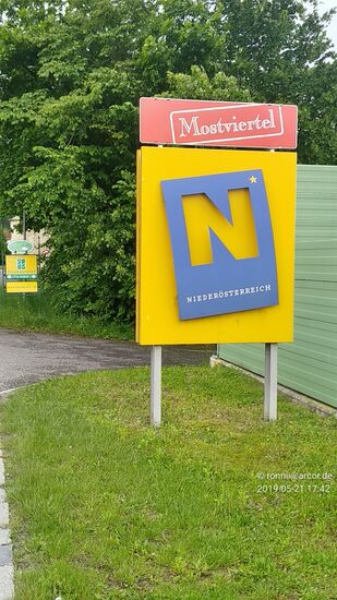 Nachdem die Enns auf der Straße direkt über das Kraftwerk Mühlrading überquert ist, befahre ich das dritte österreichische Bundesland an diesem Tag, nämlich:
Niederösterreich mit dem Zusatzschild an dieser Stelle für das bei Touristen bestens bekannte Mostviertel, dem südwestlichen Teil Niederösterreichs.
Die sogenannten "Viertel" in Niederösterreich haben dabei seit Bildung der Politischen Bezirke in 1868 keine rechtliche Grundlage mehr und stellen reine Landschaftsbezeichnungen dar.