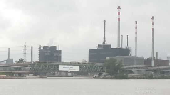 Von der Position des vorigen Bildes aus kann man in der Ferne einen Teil der mächtigen Produktionsanlagen des österreichischen stahlbasierten 
Technologie- und Industriegüterkonzerns voestalpine AG erblicken, die 1995 aus dem 1946 gegründeten Stahlkonzern VÖEST hervorging. 
In 500 Konzerngesellschaften und -standorten in 50 Ländern auf allen Kontinenten vertreten, sind weltweit etwa 52.000 Mitarbeiter beschäftigt, 
davon derzeit auf meine direkte Anfrage bei der voestalpine AG gegen Ende Januar 2020 allein 11.700 am Standort Linz.
Übrigens mündet, hier nicht sichtbar, etwa 2km stromabwärts am linken Ende des Werksgeländes die im Salzkammergut entspringende Traun, die auch den Hallstätter See, sowie den Traunsee durchfließt, in die Donau und bildet die Grenze 
zum Naturschutzgebiet Traun-Donauauen.