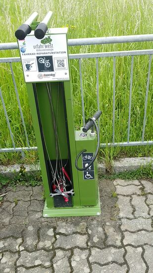 Gleich danebenstehend eine stationäre Fahrrad-Reparaturstation mit integrierter Luftpumpe und angeseiltem Standard-Werkzeug. An der oberen Vorrichtung läßt sich das Gefährt stabil für eine evtl. Maßnahme einhängen.
Gesehen in Aschach an der Donau.