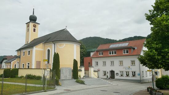 In Wesenufer steuere ich nochmals kurz mein letztes Quartier, die Pension Schütz rechts neben der unter Denkmalschutz stehenden und in 1325 erstmals erwähnten Kirche St. Wolfgang an, um mich bei der Pensionswirtin für die motivierenden Worte zum Besuch des Ausblicks zu bedanken.
Übrigens befindet sich auch diese Unterkunft mitsamt Essensraum und Gästezimmern in bestens gepflegtem Erscheinungsbild, also alle verfügbaren Daumen hoch.