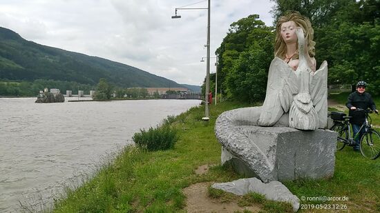 Darf ich vorstellen:
Die Nixe Isa, eine Schwester der Loreley am Rhein (s. folgende Tafel).
Am Kraftwerk Jochenstein im Hintergrund können Fußgänger und Radfahrer ganzjährig die Donau zwischen Österreich und Deutschland überqueren.
Das Kraftwerk hat fünf Kaplanturbinen mit einer Ausbauleistung von 132 MW  und ein mittleres Jahresarbeitsvermögen von 850 Mio. kWh.