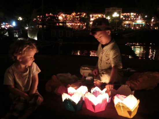 Junge, der die schwimmenden Kerzen am Ufer verkauft