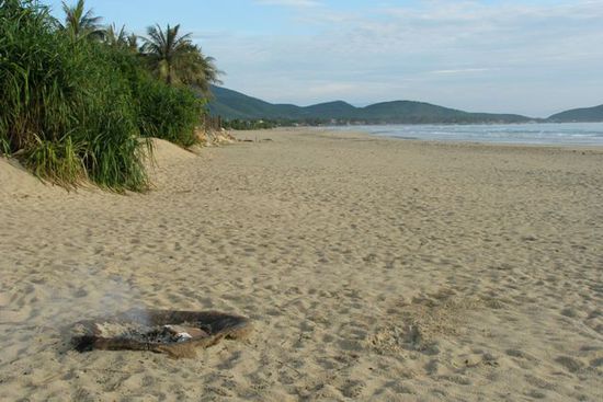 Jede Menge Strand fuer 15 Leute, im Vordergrund qualmt noch das vorabendliche Lagerfeuer.