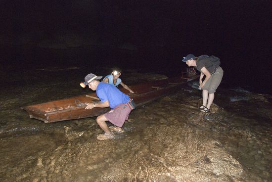 Sandra schaut interessiert zu, wie die zwei Bootsführer das Boot über die Sandbank schieben.