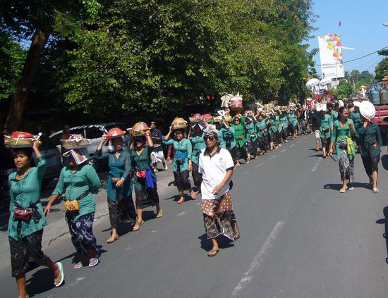 In Bali herrscht Religionsfreiheit, aber über 90% der Balinesen sind Hindus und glauben daher an Wiedergeburt der Seele. Ein Begräbnis bzw. die Verbrennungsfeier ist eine aufwendige und kostspielige Zeremonie. Die meisten Familien sind gezwungen, ihre Toten zuerst zu begraben und müssen dann jahrelang sparen für die Kremation.
An unserem letzten Urlaubstag gabs in Sanur so eine Verbrennunszeremonie. Voran schritten viele Frauen in den gleichen Farben gekleidet mit Opfergaben auf dem Kopf