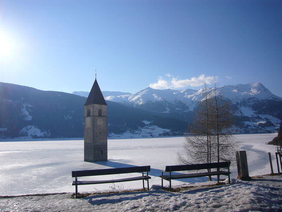 zugefrorener Reschensee mit Kirchturm vom versunkenem Dorf Alt-Graun