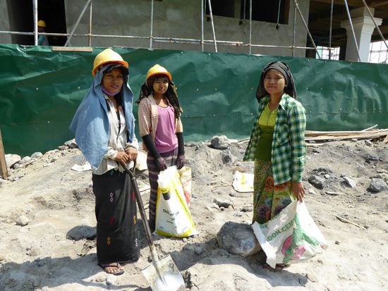 diese 3 hübschen Mädchen arbeiten am Bau eines großen Hotels - sie mischen die Malte zum Verputzen