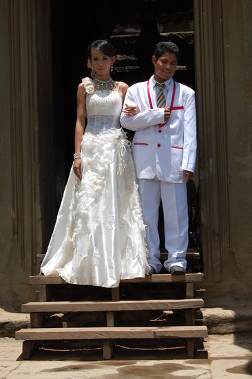 Ein kambodschanisches Brautpaar beim Footoshooting. Man beachte den etwas zu großen Anzug des Bräutigams . Das Kleid der Braut wurde von hinten mit Sicherheitsnadeln enger gemacht.