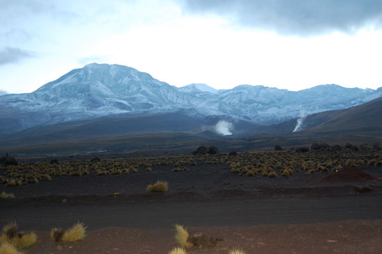 Um den Krater die schneebedeckten Berggipfel.