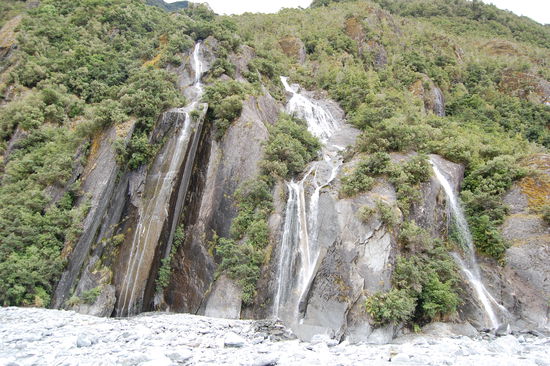 An den Felsen ergiessen sich kleine Wasserfaelle.