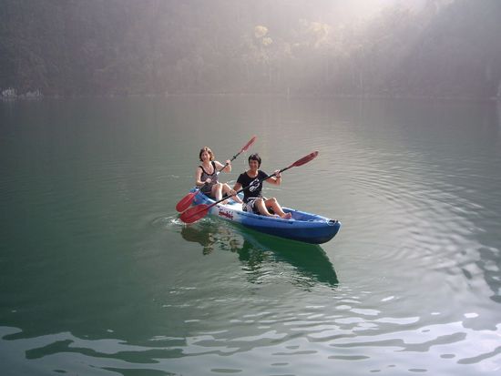 Kajak fahren bei einer herrlichen Lichstimmung am Morgen, wenn die Sonne ueber die Felsen klettert und die Spitzen der Felsen noch in Wolken gehuellt sind.