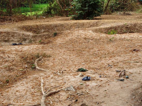 In diesem Massengrab sieht man Kleidungsreste und Knochen im Boden