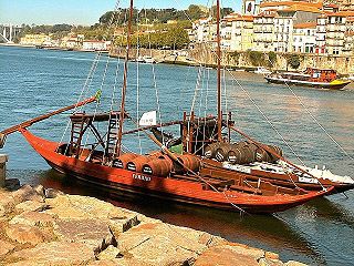 Früher wurde der Portwein in diesen Holzfässern und auf diesen Schiffen, den Barcos rabelos hierher nach Gaia gebracht. In den Weinkellern am Ufer des Douro reifen die Weine zu edlen Portweinen heran.