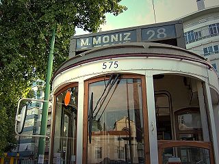 In der Fensterscheibe spiegelt sich das Portal zum Cemitério dos Prazeres wider.