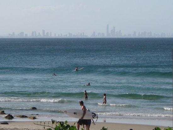 Surfer, im Hintergrund die "Gold Coast" mit "Surfers Paradise" (hoechstes Gebaeude)