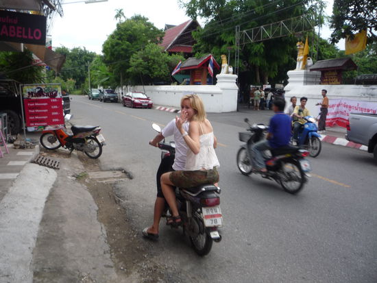 Kaum raus aus dem Tempel (Eingang siehe Hintergrund)schoss es Ines in den Kopf: Sie wollte sich von 2 thailaendischen Nicht-Hetero-Friseuren neue Straehnchen machen lassen. Da sie blank war brachte sie einer der Friseure mit seinem Moped zur naechsten Bank. Hannes hatte keine Bedenken....u ging derweil zu einer 1stuendigen Thai-Massage!(fuer nur 3Euro!!!)