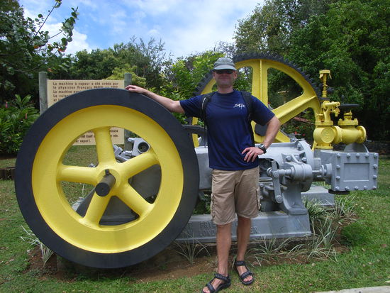 Hier seht Ihr einen modernen Karibik-Urlauber 
vor einer altmodischen Zuckerrohr-Presse