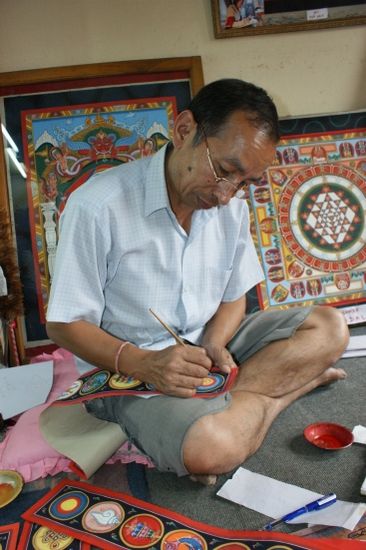 Wir kaufen uns ein "Bild" mit den Glueckssymbolen. Madhu in seinem Atelier.