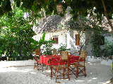 Essbereich im Grand Bungalow in Jambiani, im Hintergrund ist ein Bungalow zu sehen.